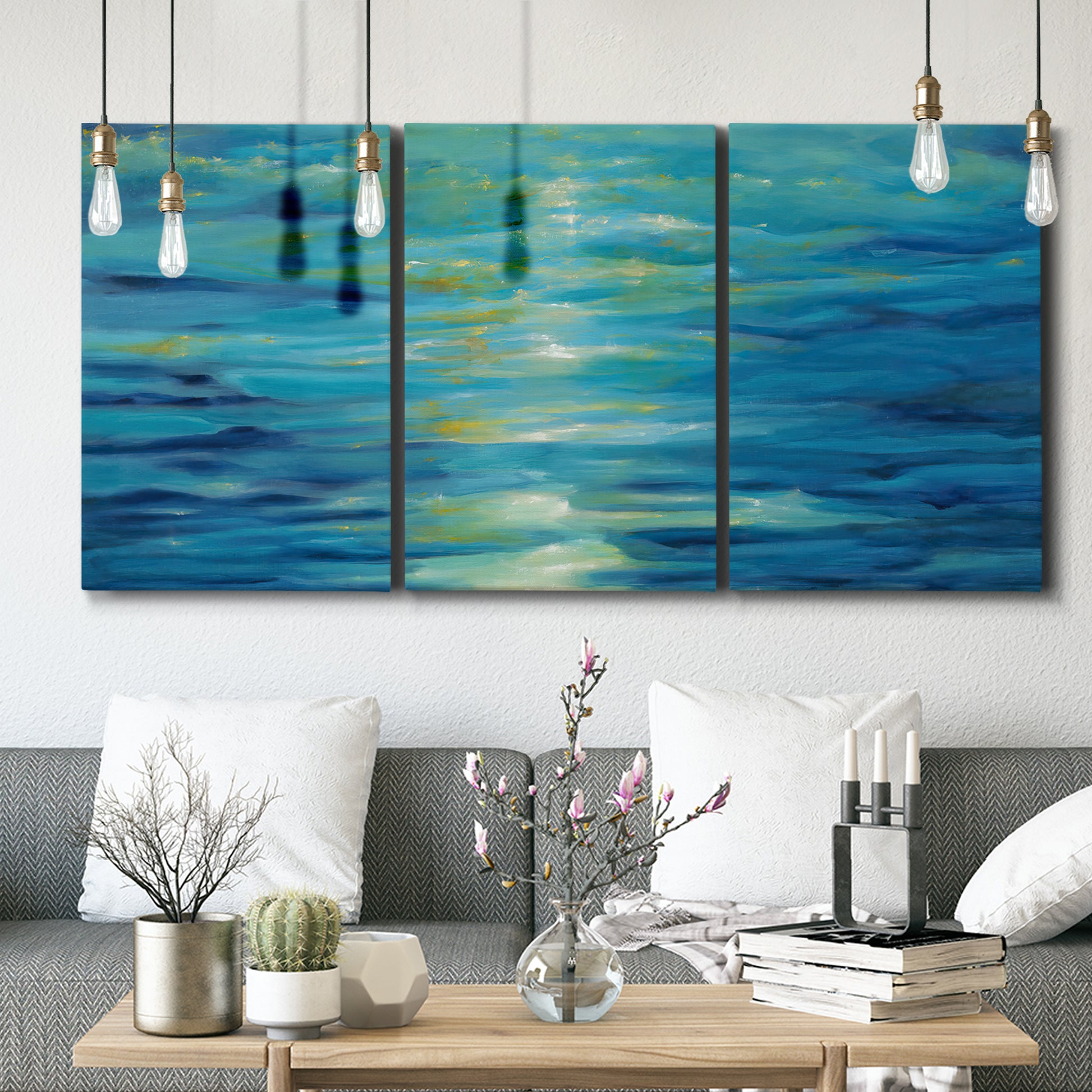 Three-panel canvas wall art featuring deep blue ocean water abstraction, displayed in a modern living room above seating.