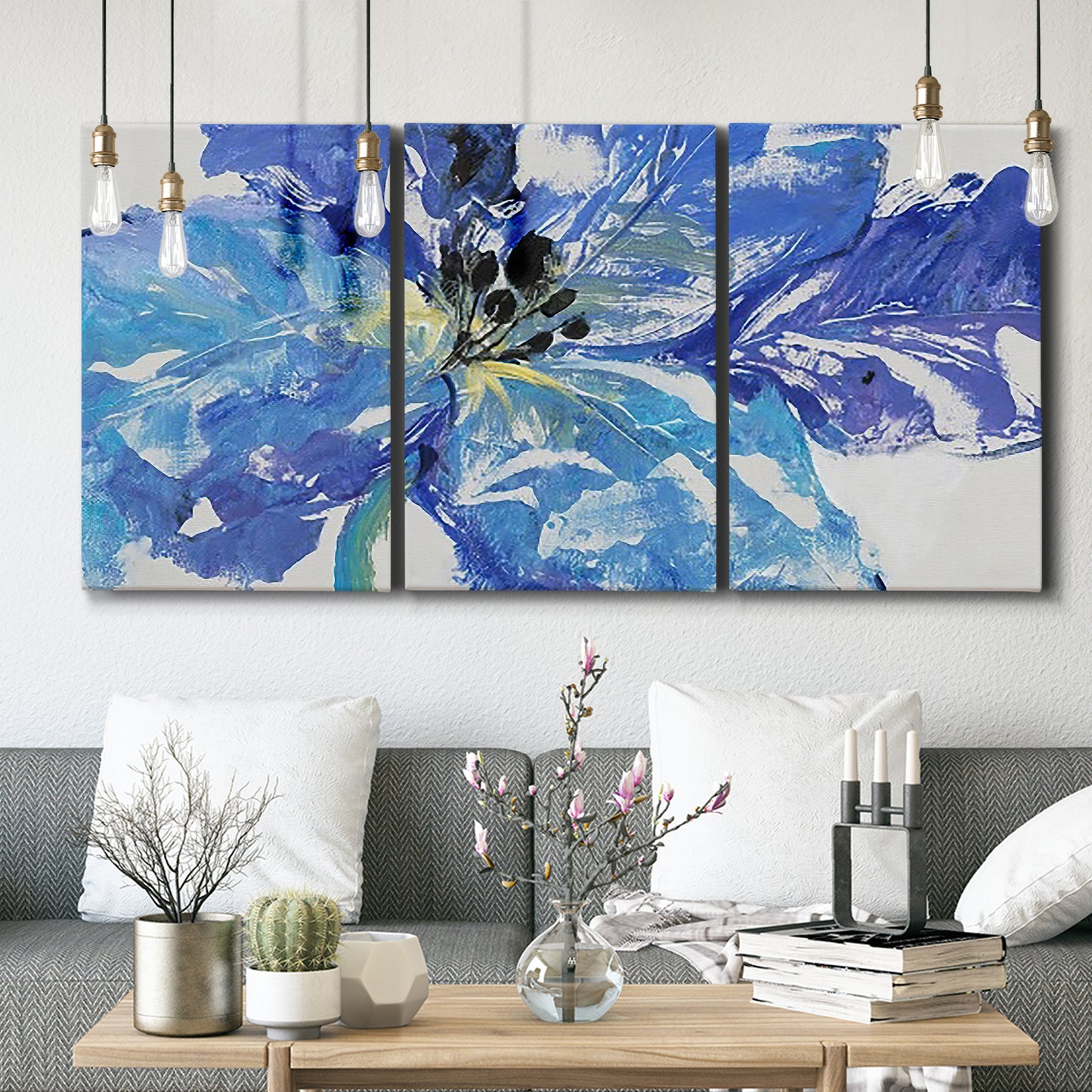 Three-panel canvas wall art featuring blue floral botanical close up, displayed in a modern living room above seating.