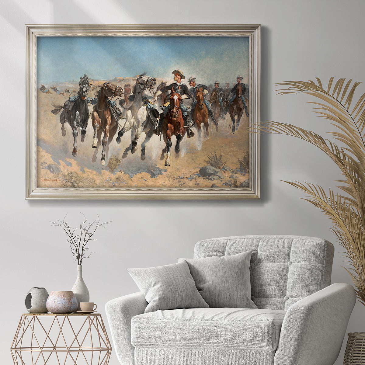 Impressionist western action scene by Frederic Remington in an ornate champagne frame displayed in a bright interior setting.