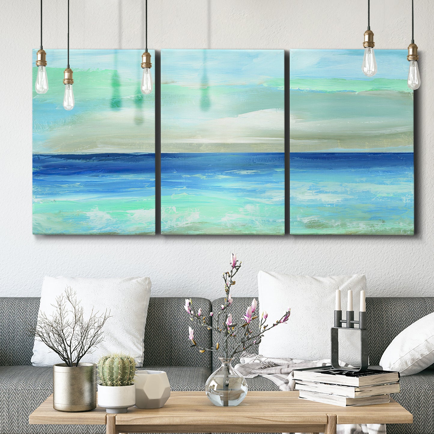 Three-panel canvas wall art featuring vast open blue ocean horizon, displayed in a modern living room above seating.