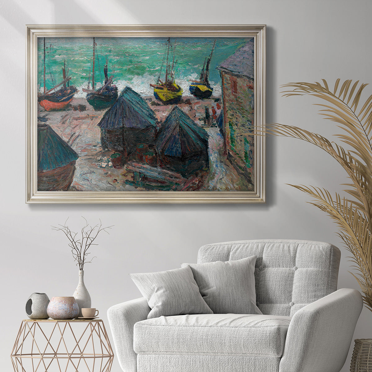 Impressionist coastal beach scene with boats by Claude Monet in an ornate champagne frame displayed in a bright interior setting.