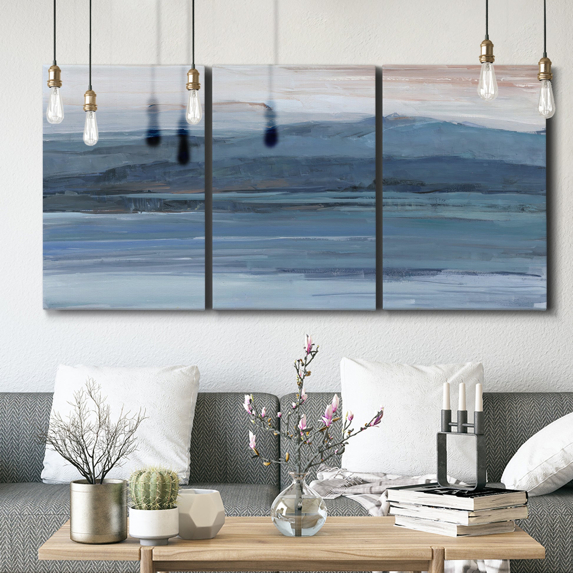 Three-panel canvas wall art featuring wide lake with distant shoreline, displayed in a modern living room above seating.