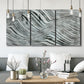 Three-panel canvas wall art featuring coastal shoreline with gentle surf, displayed in a modern living room above seating.