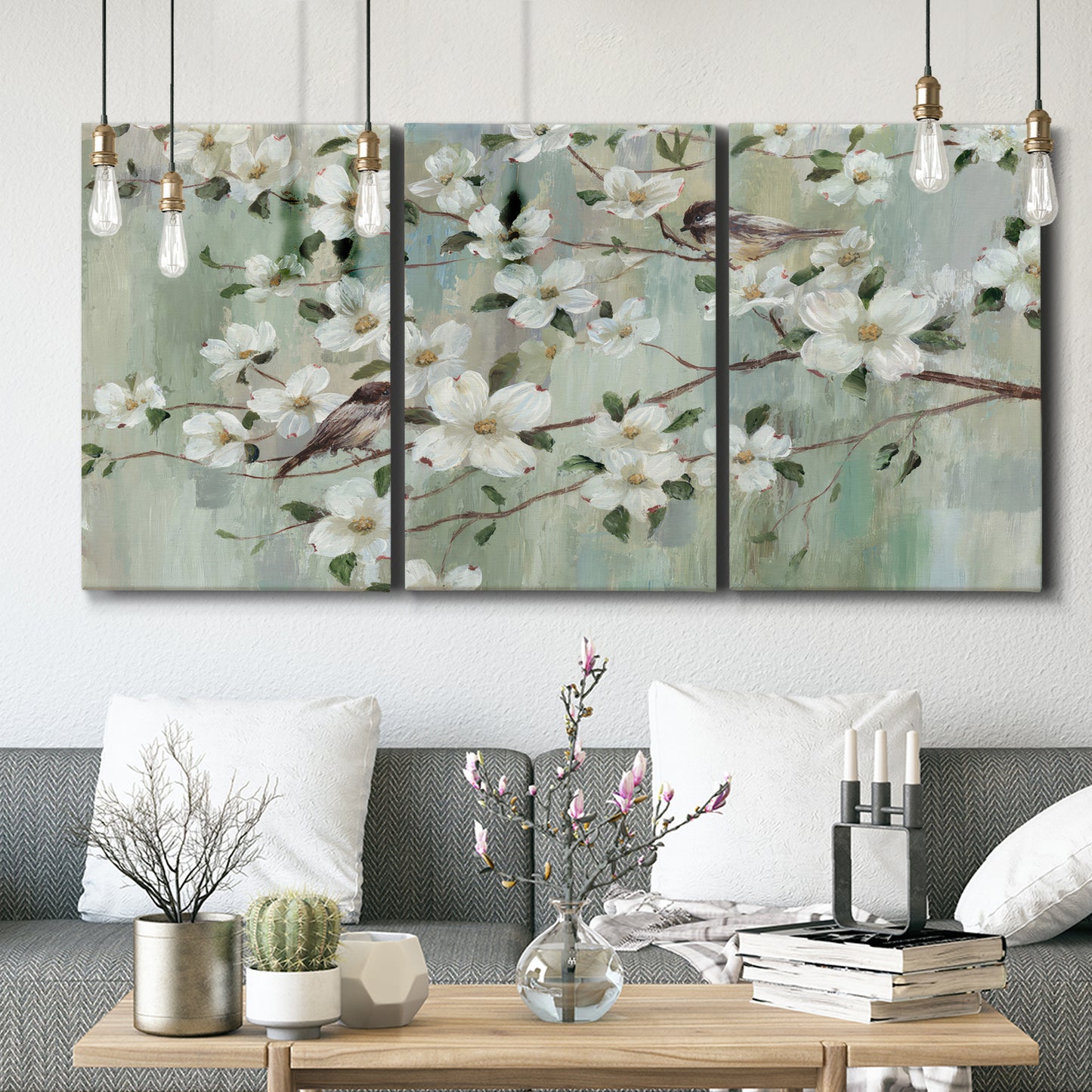 Three-panel canvas wall art featuring delicate spring blossoms with birds, displayed in a modern living room above seating.