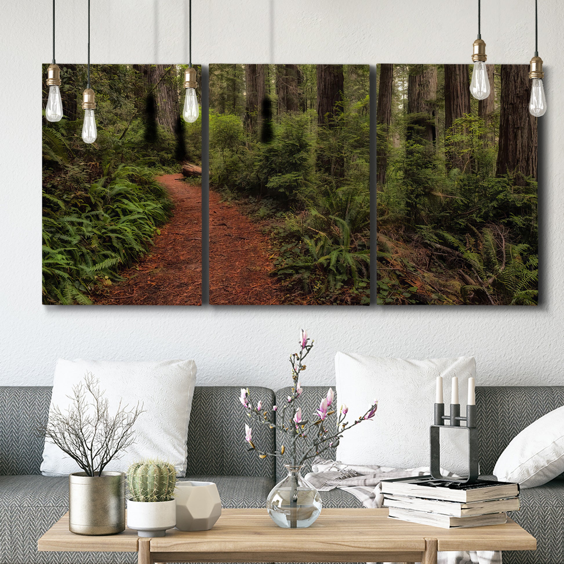 Three-panel canvas wall art featuring forest trail landscape photograph, displayed in a modern living room above seating.