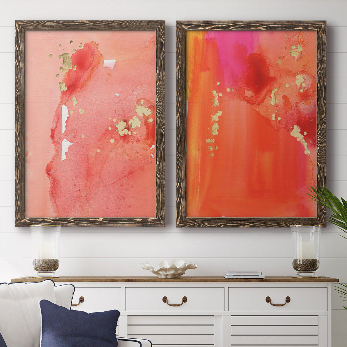 Set of two walnut barnwood framed canvas prints depicting a coordinated art pair of luminous coral orange and pink color fields with gold flecks rendered as glamorous fluid abstracts above a dining room sideboard.