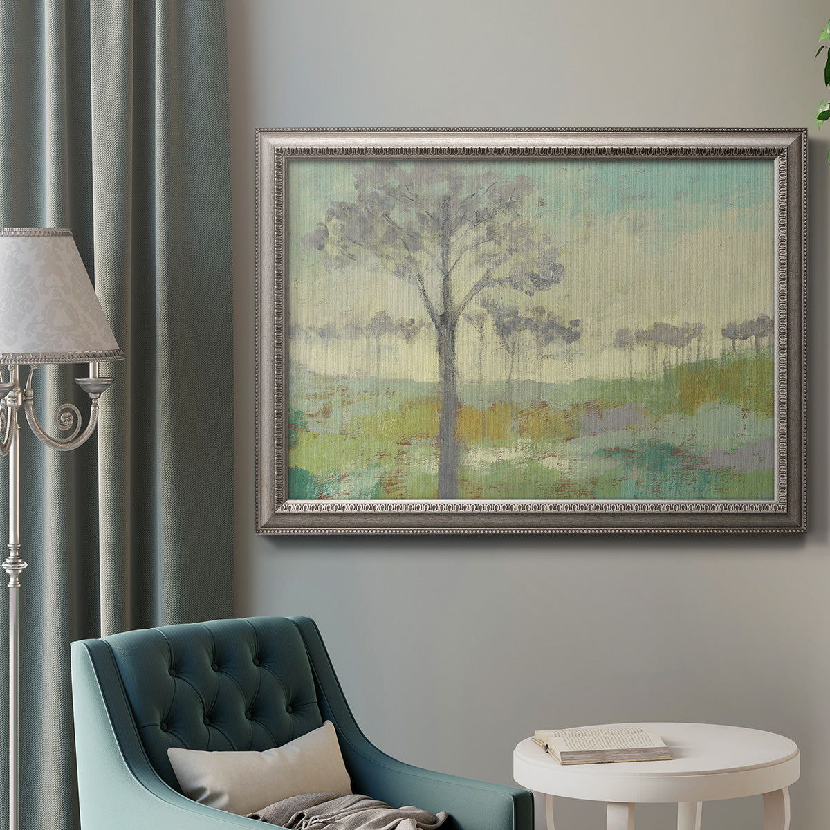 Traditional watercolor tree landscape artwork in an ornate vintage silver frame displayed in a neutral interior setting.