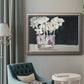 Contemporary floral watercolor with white flowers in an ornate vintage silver frame displayed in a neutral interior setting.