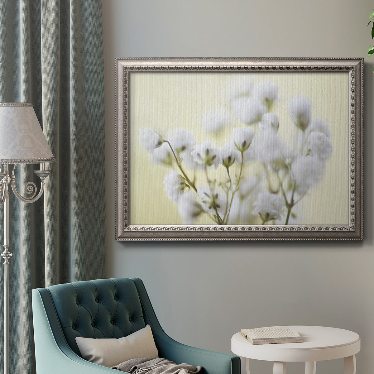 Soft-focus baby’s breath flower photograph in an ornate vintage silver frame displayed in a neutral interior setting.