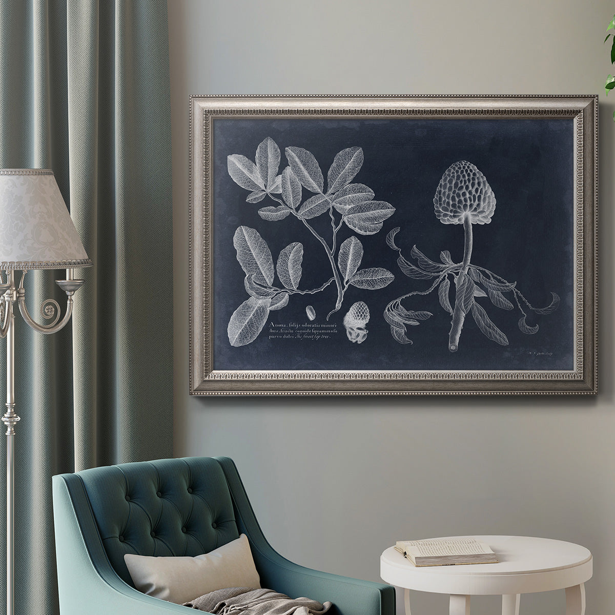 Antique botanical foliage illustration on navy background in an ornate vintage silver frame displayed in a neutral interior setting.
