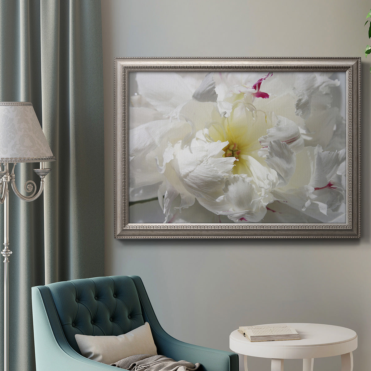 Close up view of peony petals in an ornate vintage silver frame displayed in a neutral interior setting.
