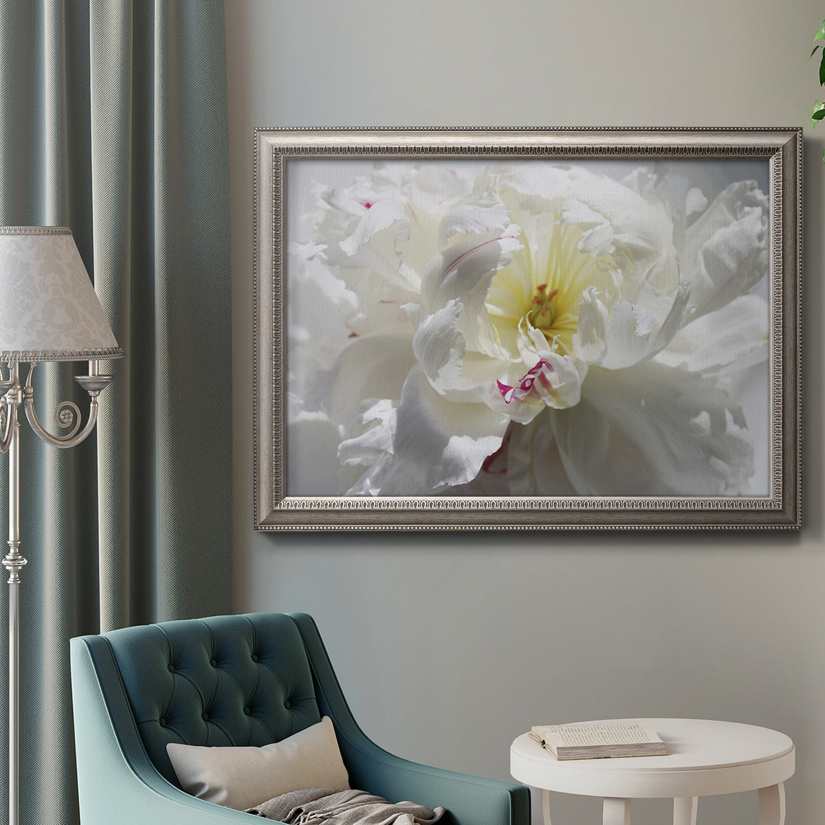 Neutral white peony photography in an ornate vintage silver frame displayed in a neutral interior setting.