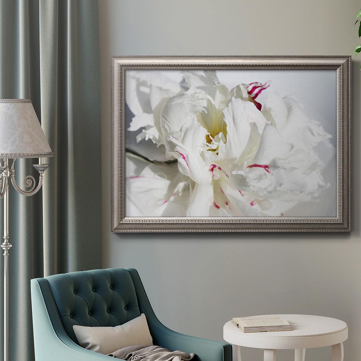 White peony close-up photography in an ornate vintage silver frame displayed in a neutral interior setting.