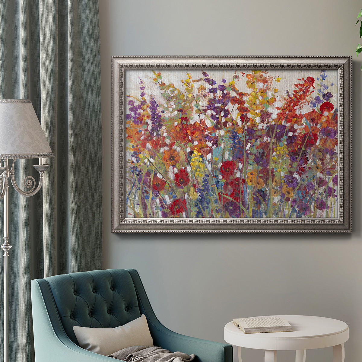 Impressionist floral bouquet artwork in an ornate vintage silver frame displayed in a neutral interior setting.