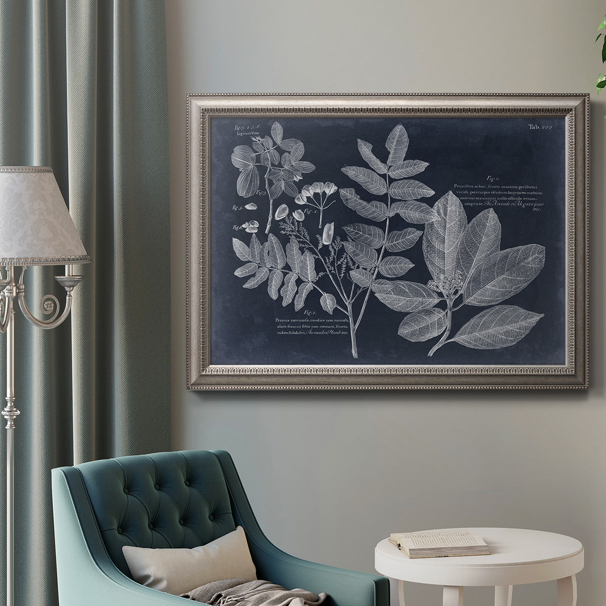 Antique botanical foliage artwork on navy background in an ornate vintage silver frame displayed in a neutral interior setting.