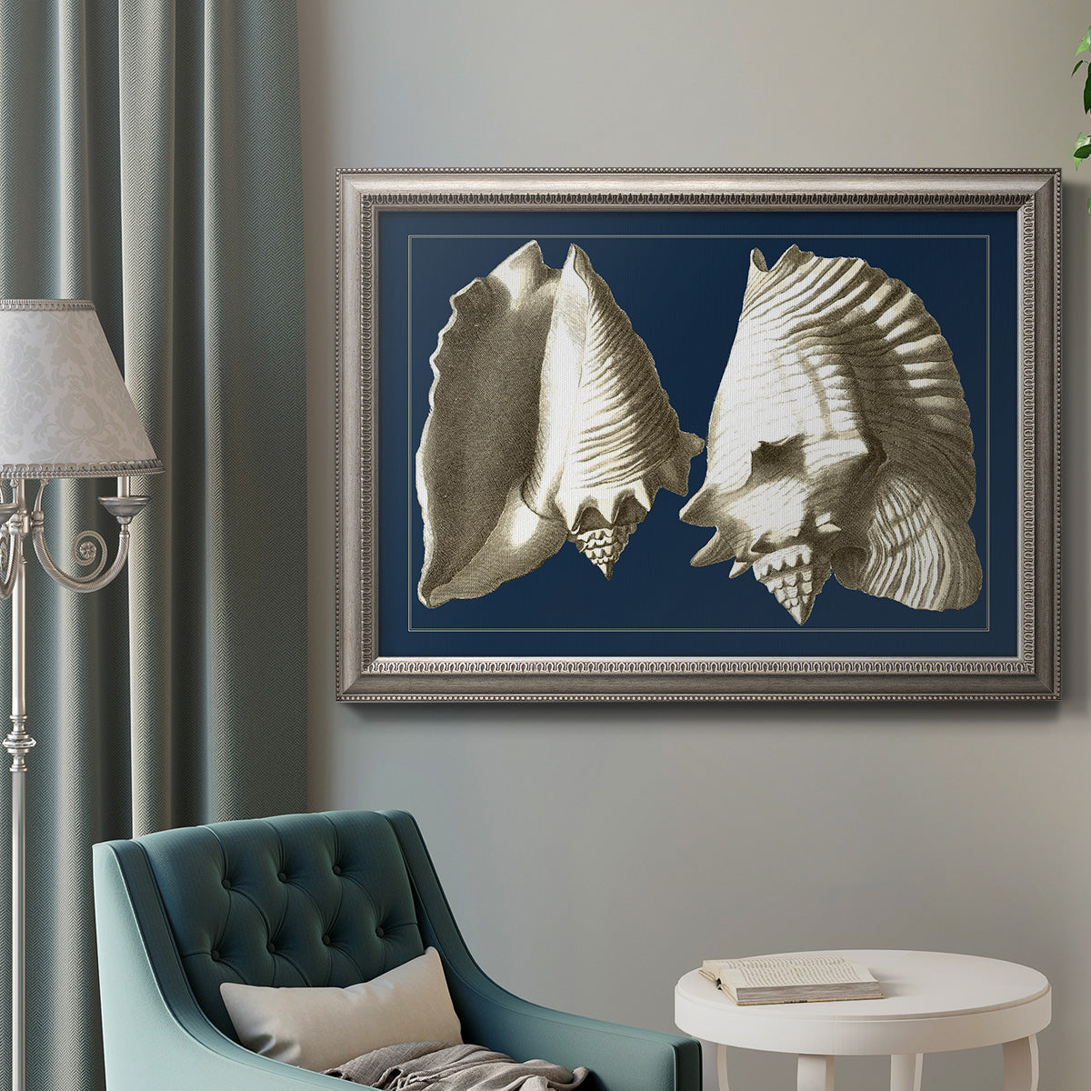 Vintage conch shell illustration on navy background in an ornate vintage silver frame displayed in a neutral interior setting.