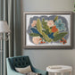 Colorful eclectic botanical artwork in an ornate vintage silver frame displayed in a neutral interior setting.