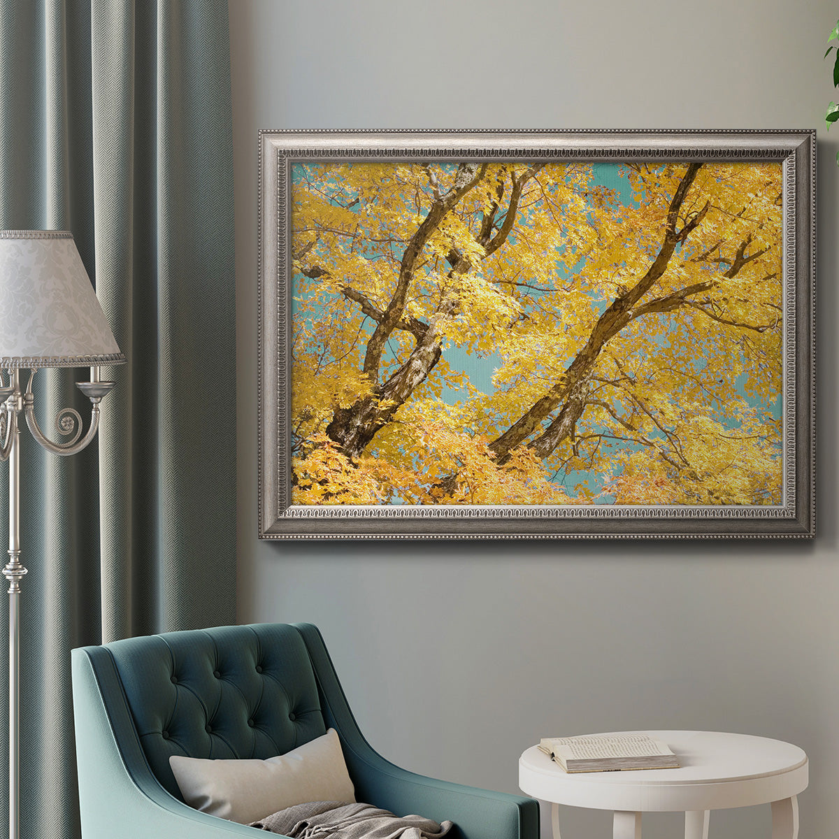 Vibrant yellow autumn leaves on branches in an ornate vintage silver frame displayed in a neutral interior setting.