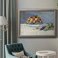 Impressionist still life painting with peaches and grapes in an ornate vintage silver frame displayed in a neutral interior setting.