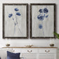 Set of two black barnwood framed canvas prints depicting a coordinated art pair of blue wildflower stems on weathered neutral paper rendered as rustic monochrome botanical paintings above a dining room sideboard.
