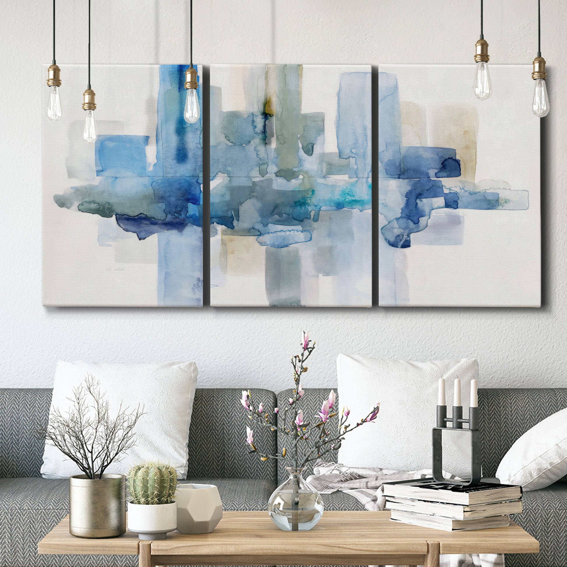 Three-panel canvas wall art featuring minimal urban skyline watercolor, displayed in a modern living room above seating.