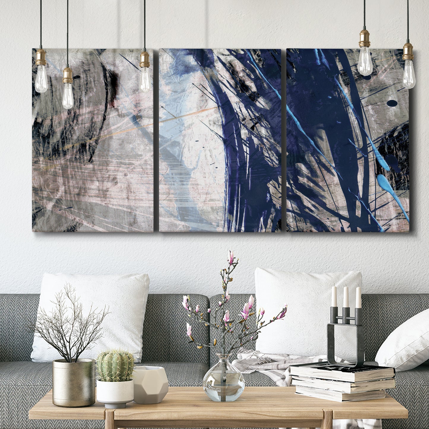 Three-panel canvas wall art featuring layered blue abstract texture, displayed in a modern living room above seating.