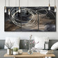 Three-panel canvas wall art featuring dark swirling abstract motion, displayed in a modern living room above seating.