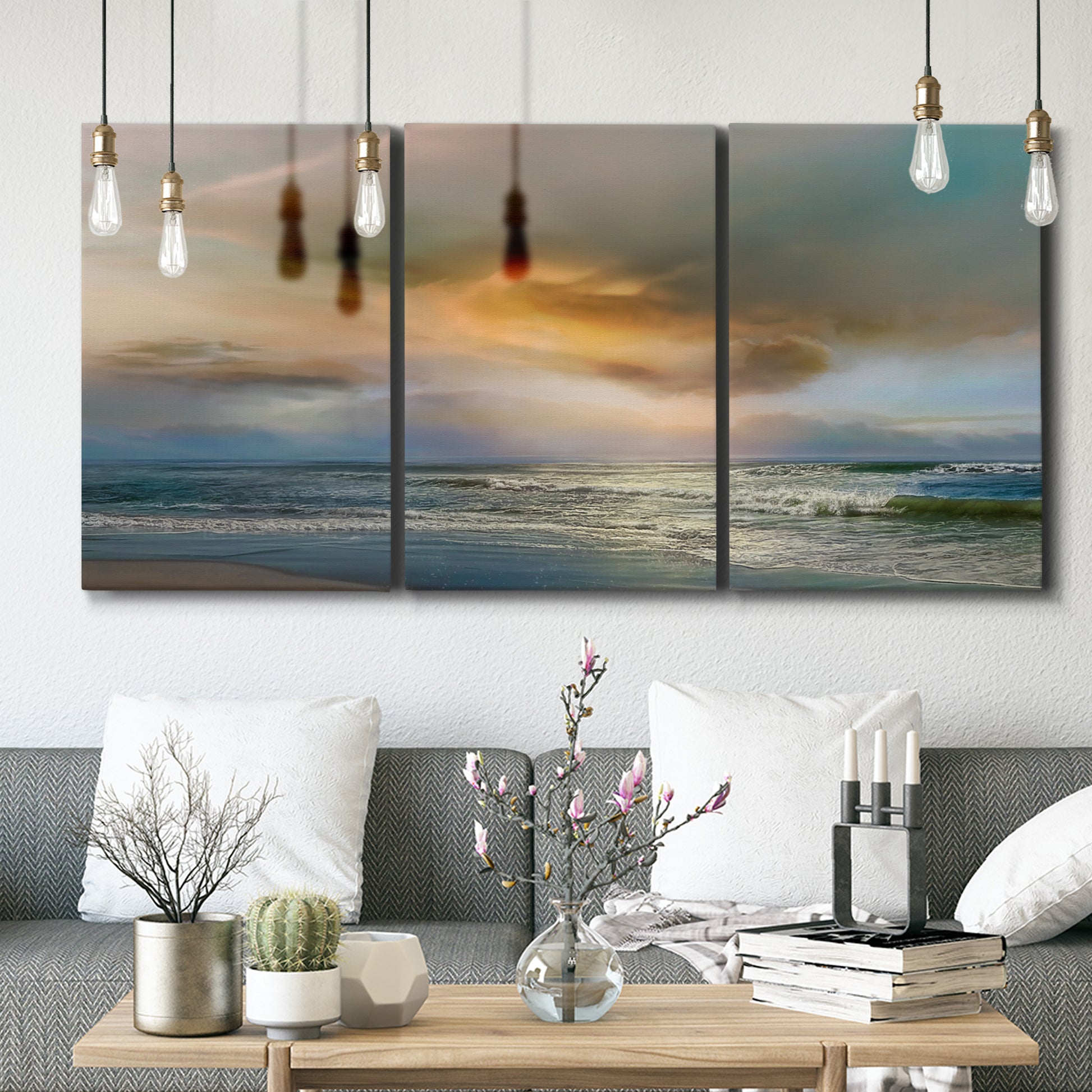 Three-panel canvas wall art featuring tranquil beach at sunset, displayed in a modern living room above seating.