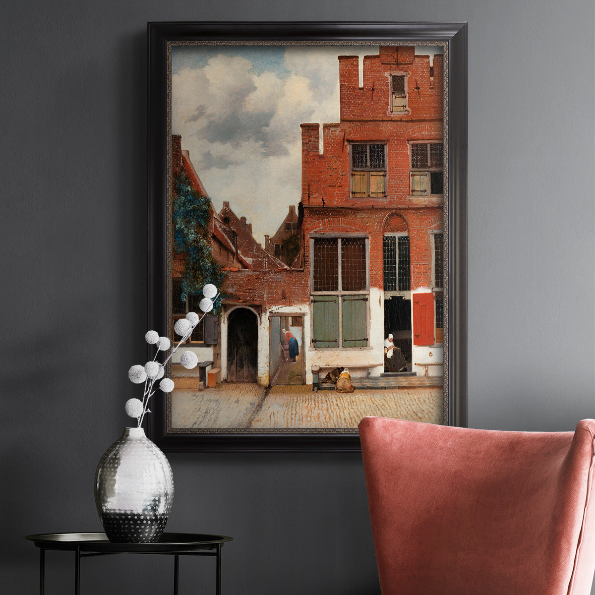 Realist city street scene by Johannes Vermeer in an ornate black frame with gilded inner detail displayed in a dark-toned interior setting.