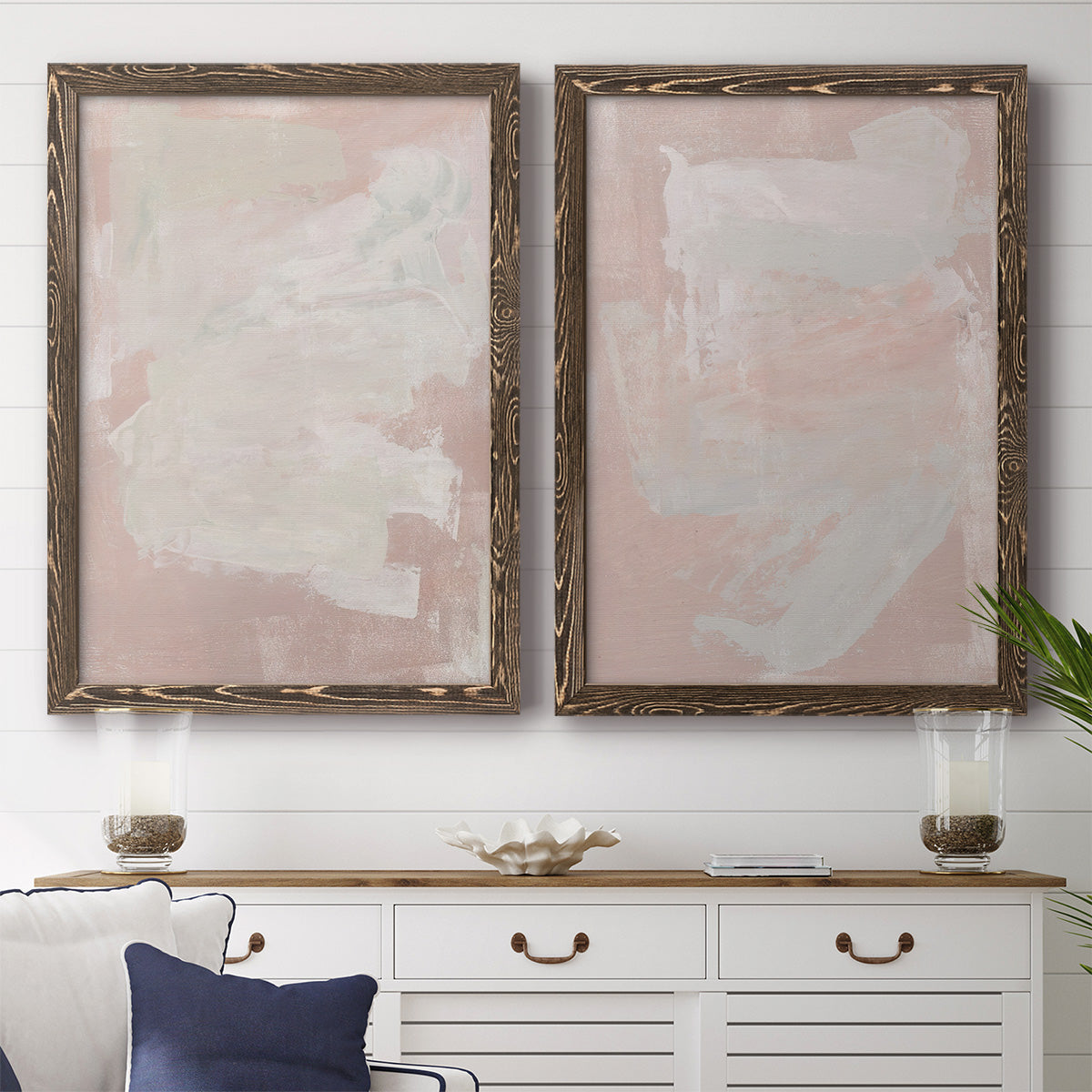 Set of two walnut barnwood framed canvas prints depicting a coordinated art pair of soft blush and white painterly fields rendered as minimalist color-field abstracts above a dining room sideboard.