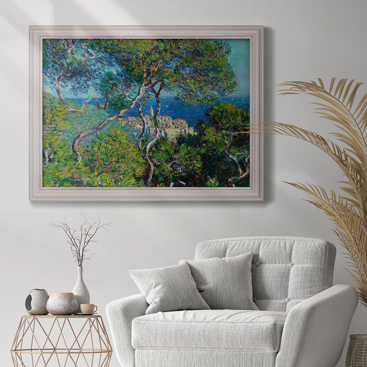 Impressionist Mediterranean coastal landscape by Claude Monet in an ornate weathered white frame displayed in a bright interior setting.