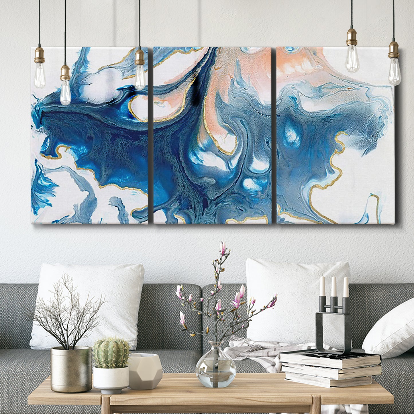 Three-panel canvas wall art featuring flowing blue abstract movement, displayed in a modern living room above seating.