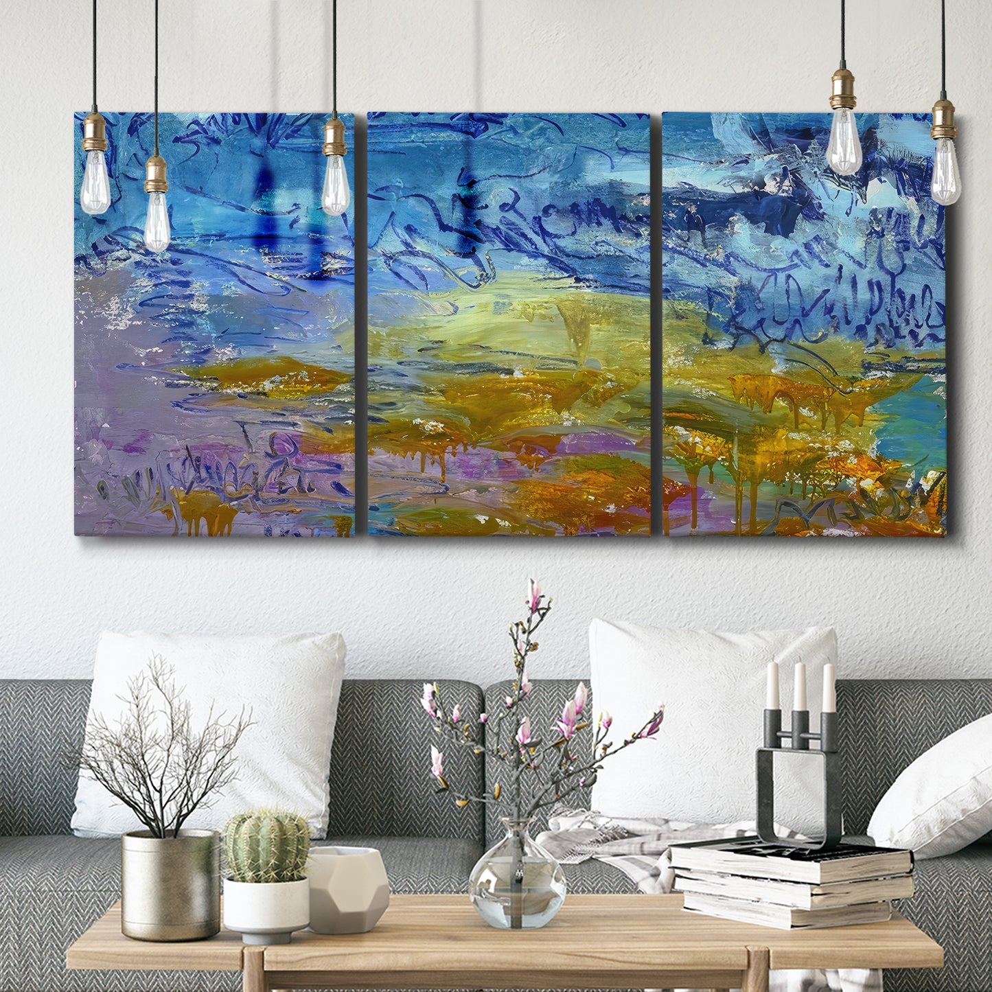 Three-panel canvas wall art featuring expressive abstract with layered color, displayed in a modern living room above seating.