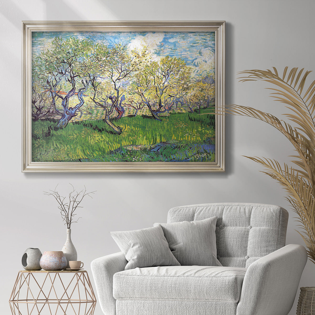 Impressionist spring orchard landscape by Vincent van Gogh in an ornate champagne frame displayed in a bright interior setting.