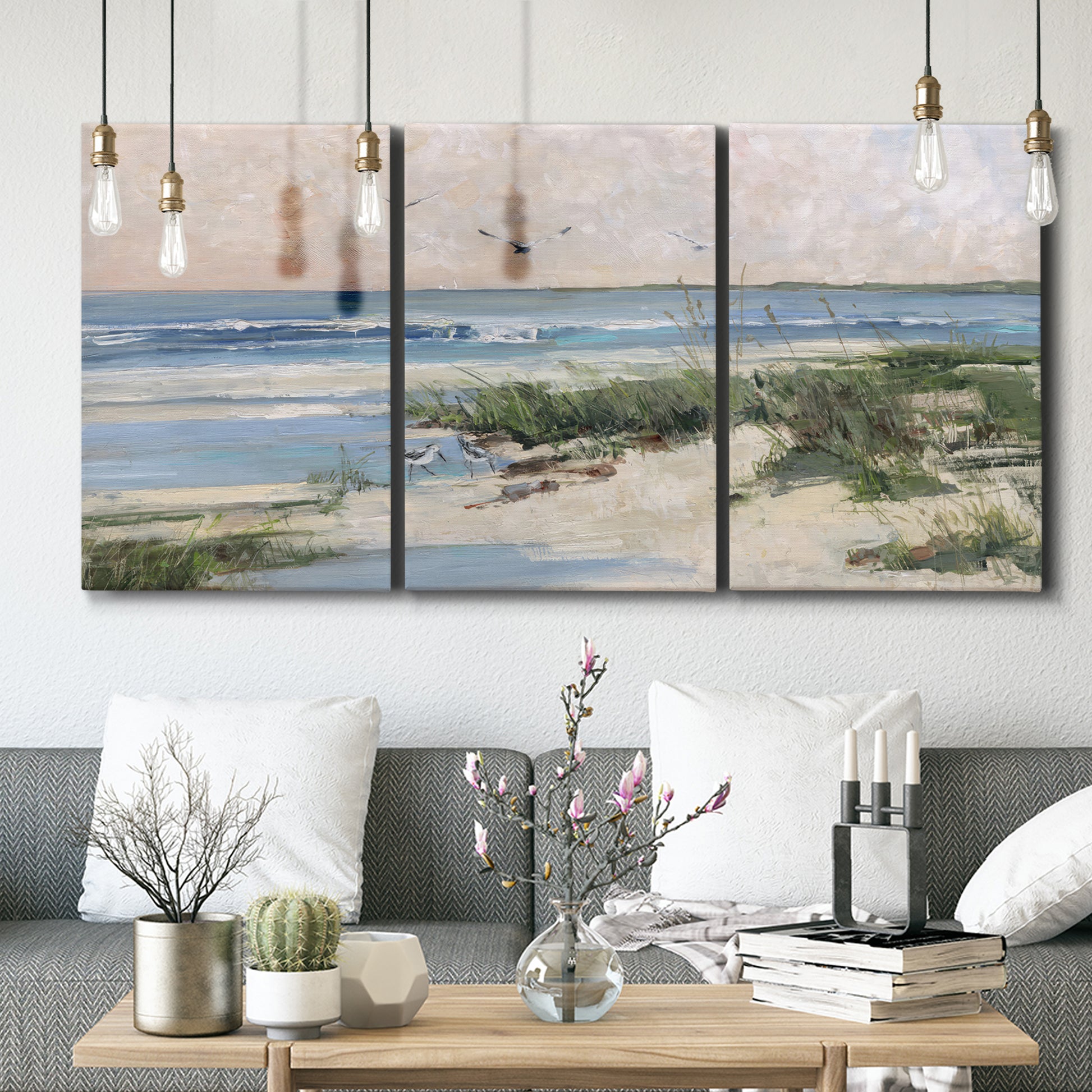 Three-panel canvas wall art featuring soft morning light over calm sea, displayed in a modern living room above seating.