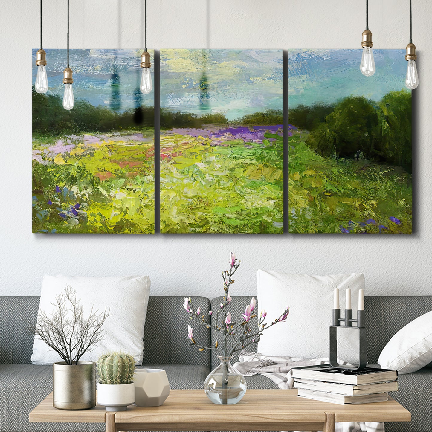 Three-panel canvas wall art featuring pastoral field with wildflowers, displayed in a modern living room above seating.