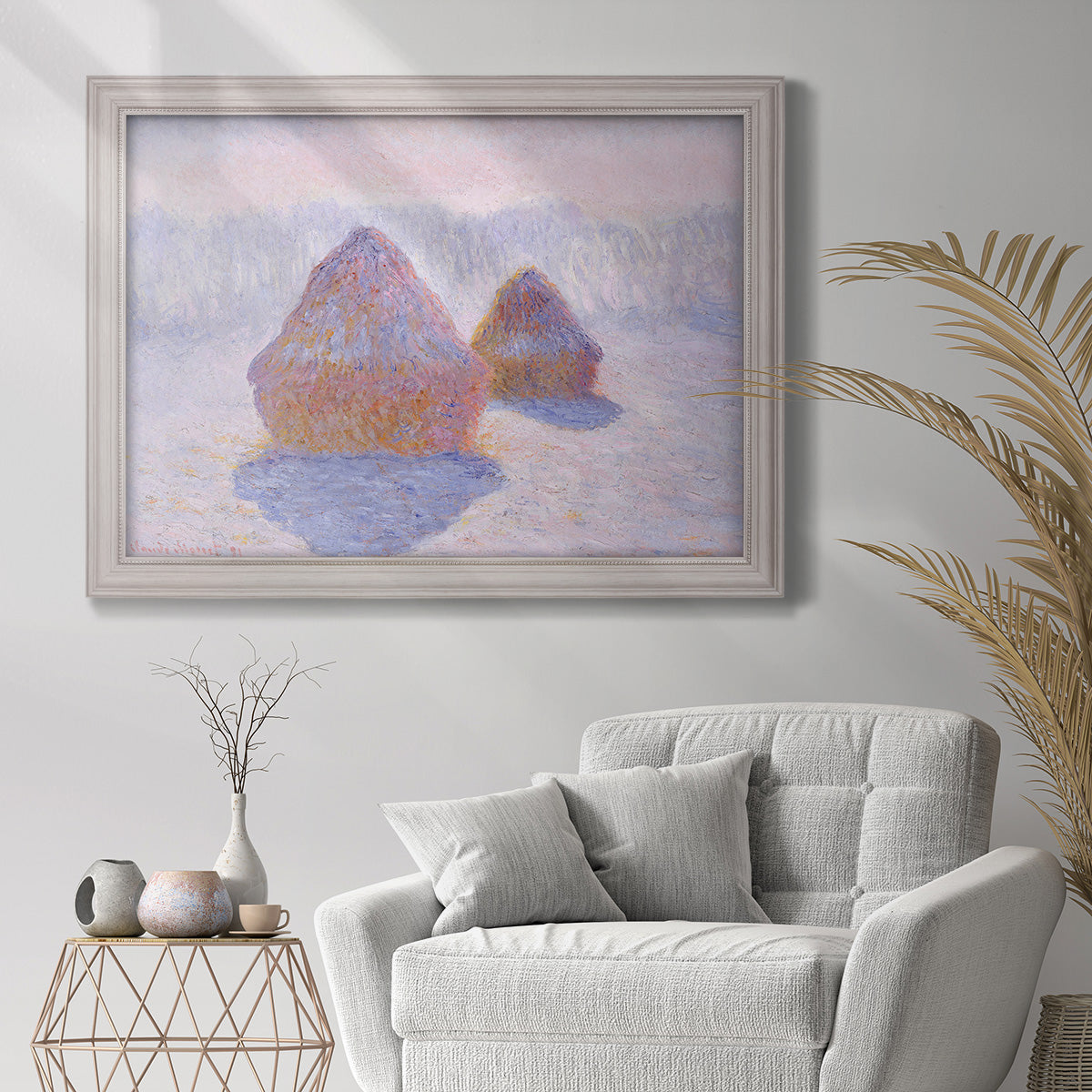 Impressionist winter haystack scene with sunlight by Claude Monet in an ornate weathered white frame displayed in a bright interior setting.