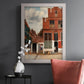 Realist city street scene by Johannes Vermeer in an ornate weathered white frame displayed in a dark-toned interior setting.