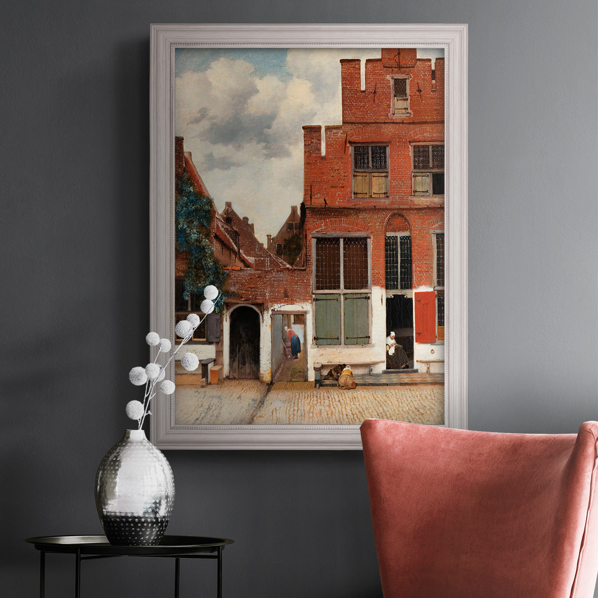 Realist city street scene by Johannes Vermeer in an ornate weathered white frame displayed in a dark-toned interior setting.