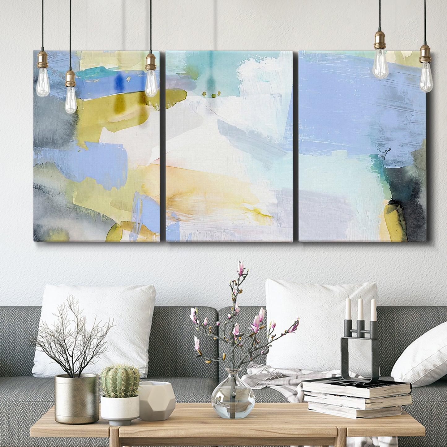 Three-panel canvas wall art featuring soft abstract spring watercolor tones, displayed in a modern living room above seating.