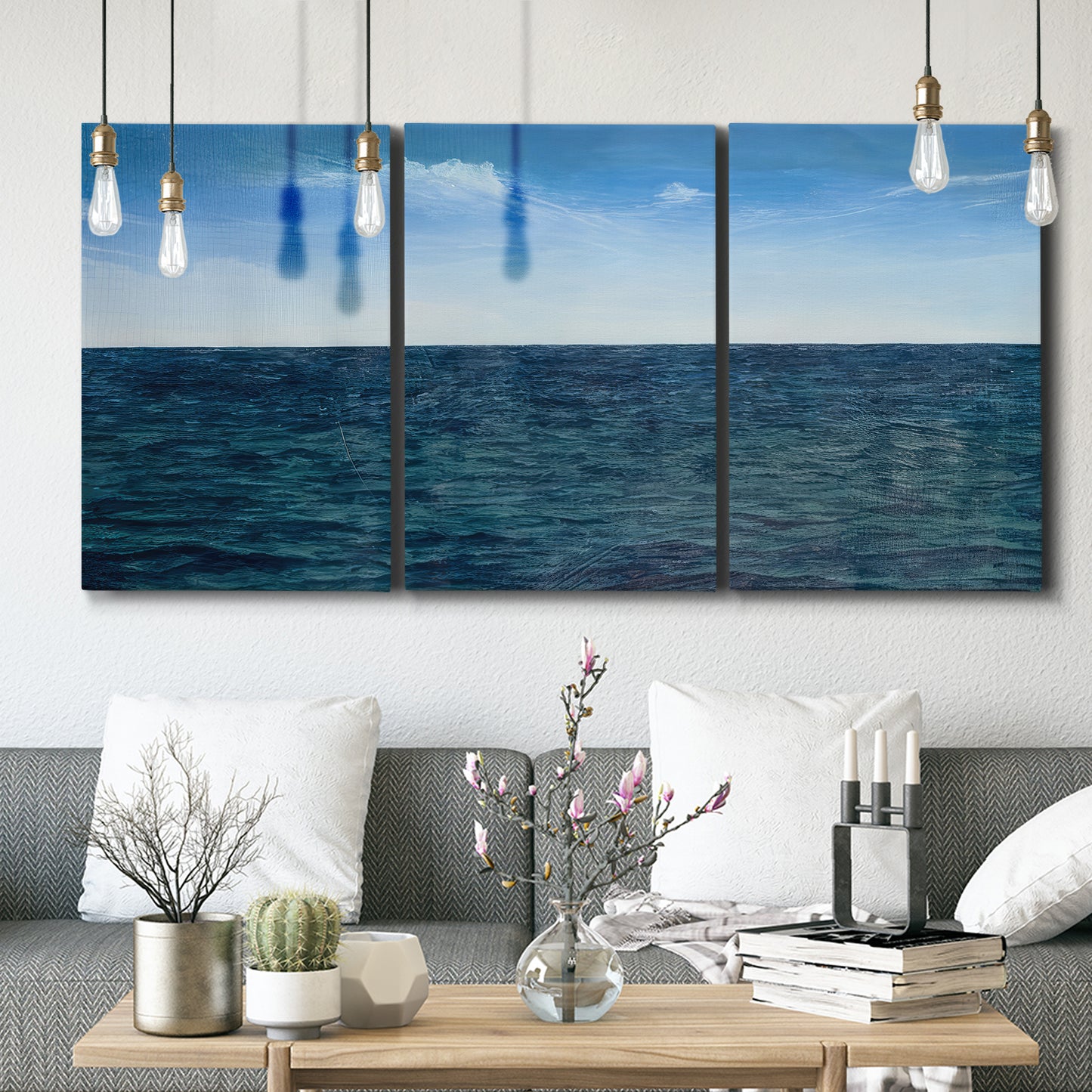 Three-panel canvas wall art featuring open water landscape with wide horizon, displayed in a modern living room above seating.