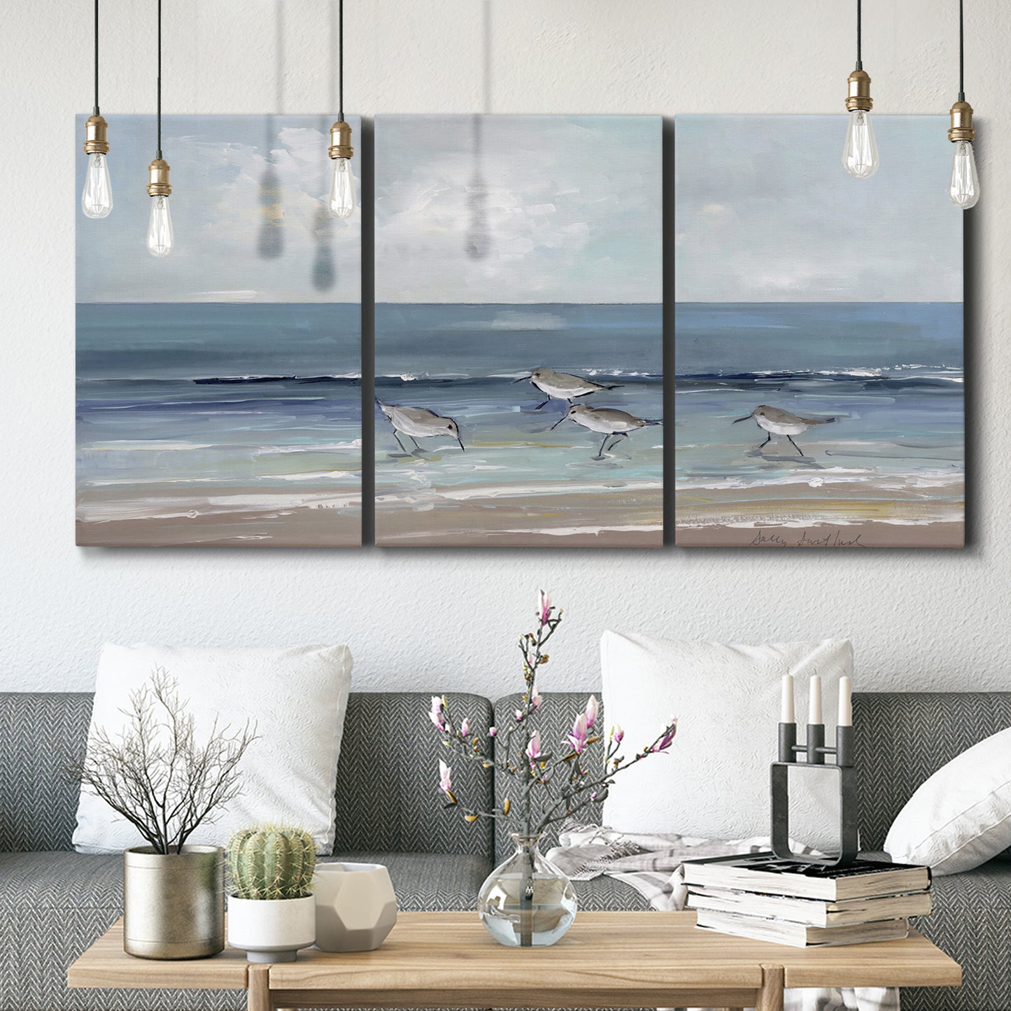 Three-panel canvas wall art featuring shore birds searching along beach, displayed in a modern living room above seating.