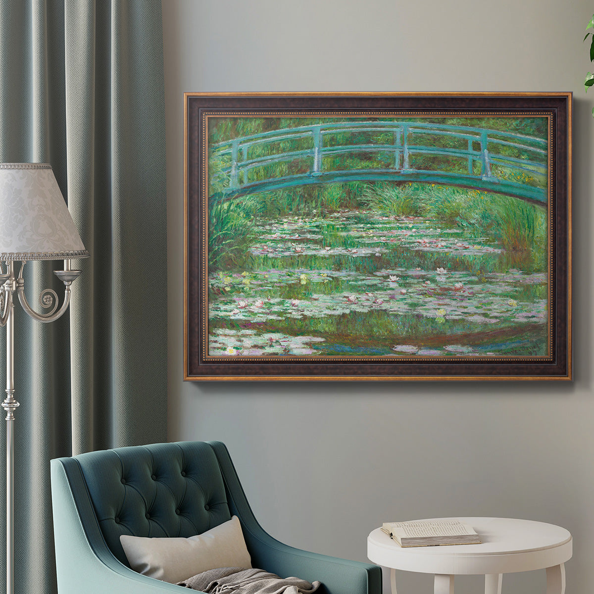 Impressionist garden scene with Japanese bridge and water lilies by Claude Monet in an ornate bronzed mahogany wood frame displayed in a bright interior setting.