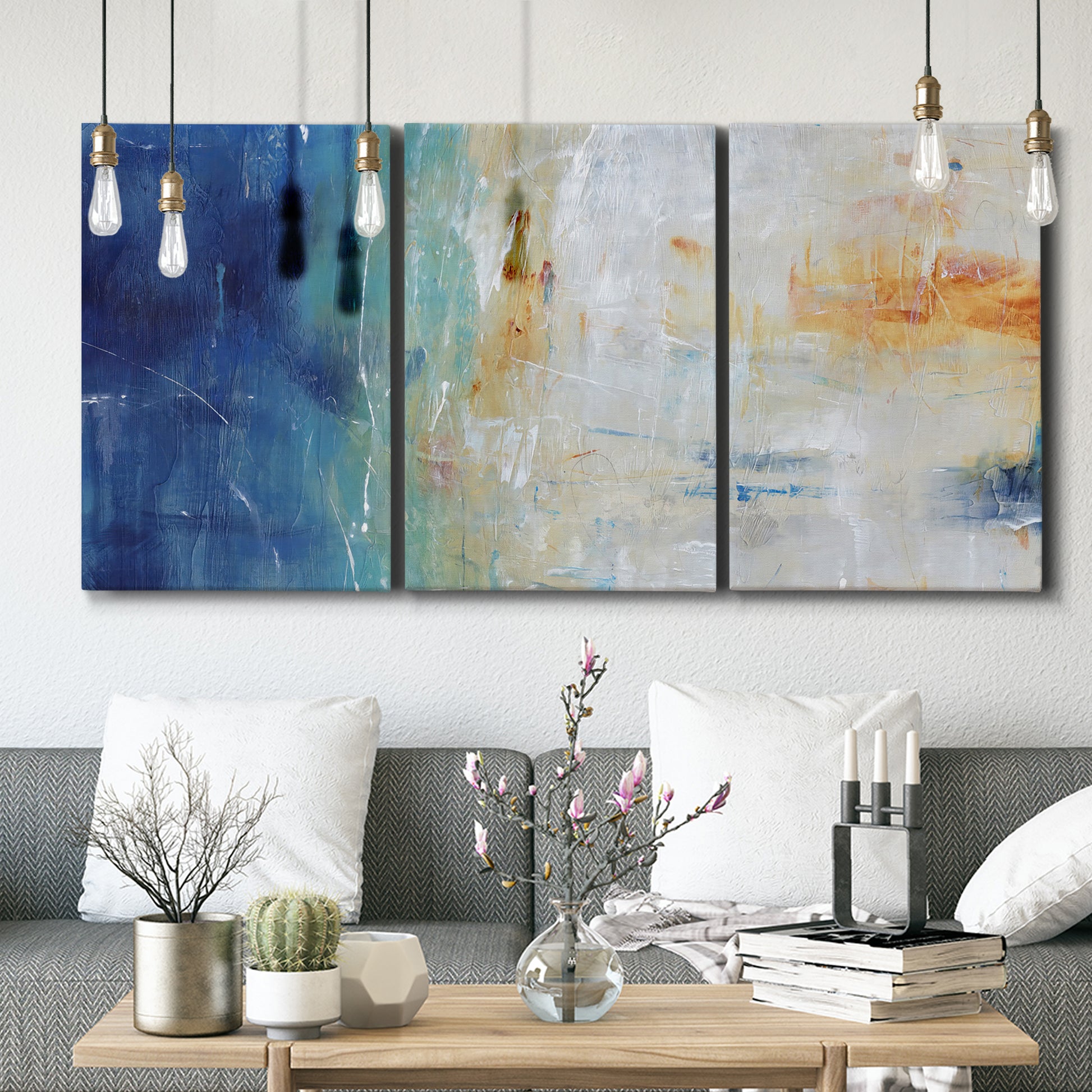 Three-panel canvas wall art featuring deep blue abstract grotto tones, displayed in a modern living room above seating.