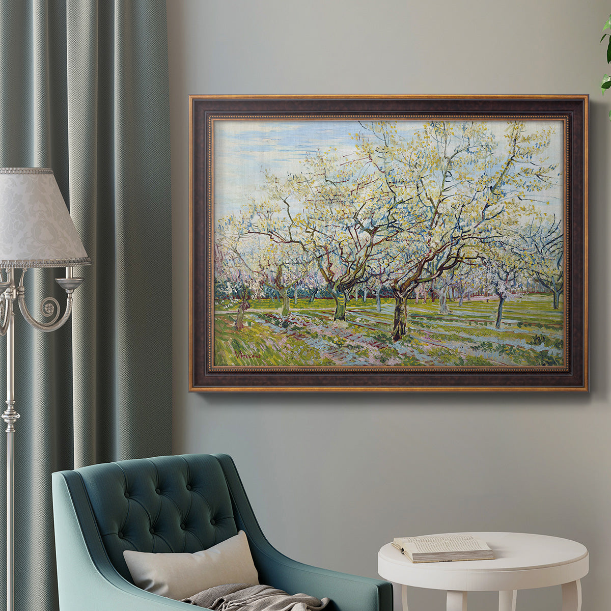 Impressionist white-blossomed orchard landscape by Vincent van Gogh in an ornate bronzed mahogany wood frame displayed in a bright interior setting.