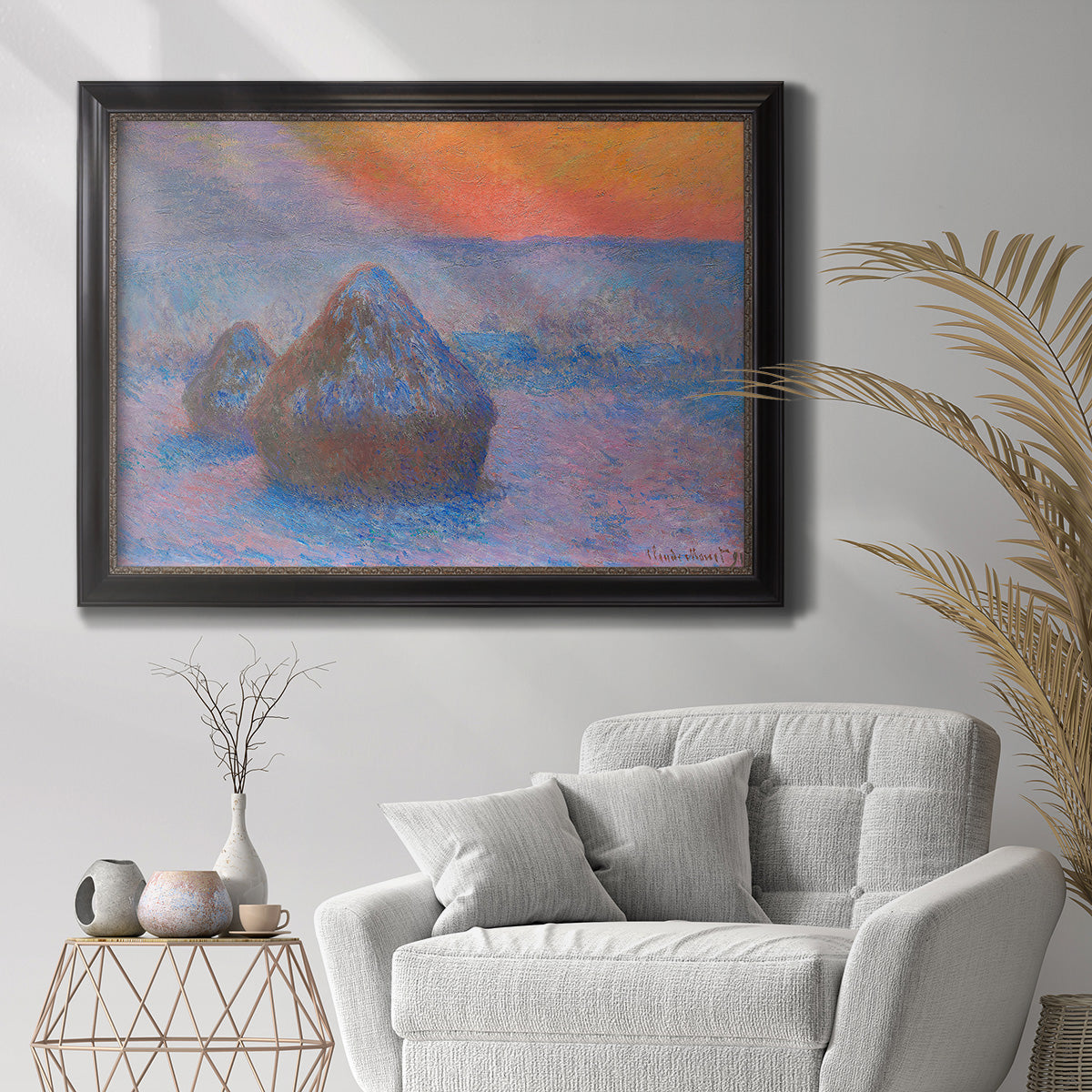 Impressionist haystack scene at sunset by Claude Monet in an ornate black frame with gilded inner detail displayed in a bright interior setting.