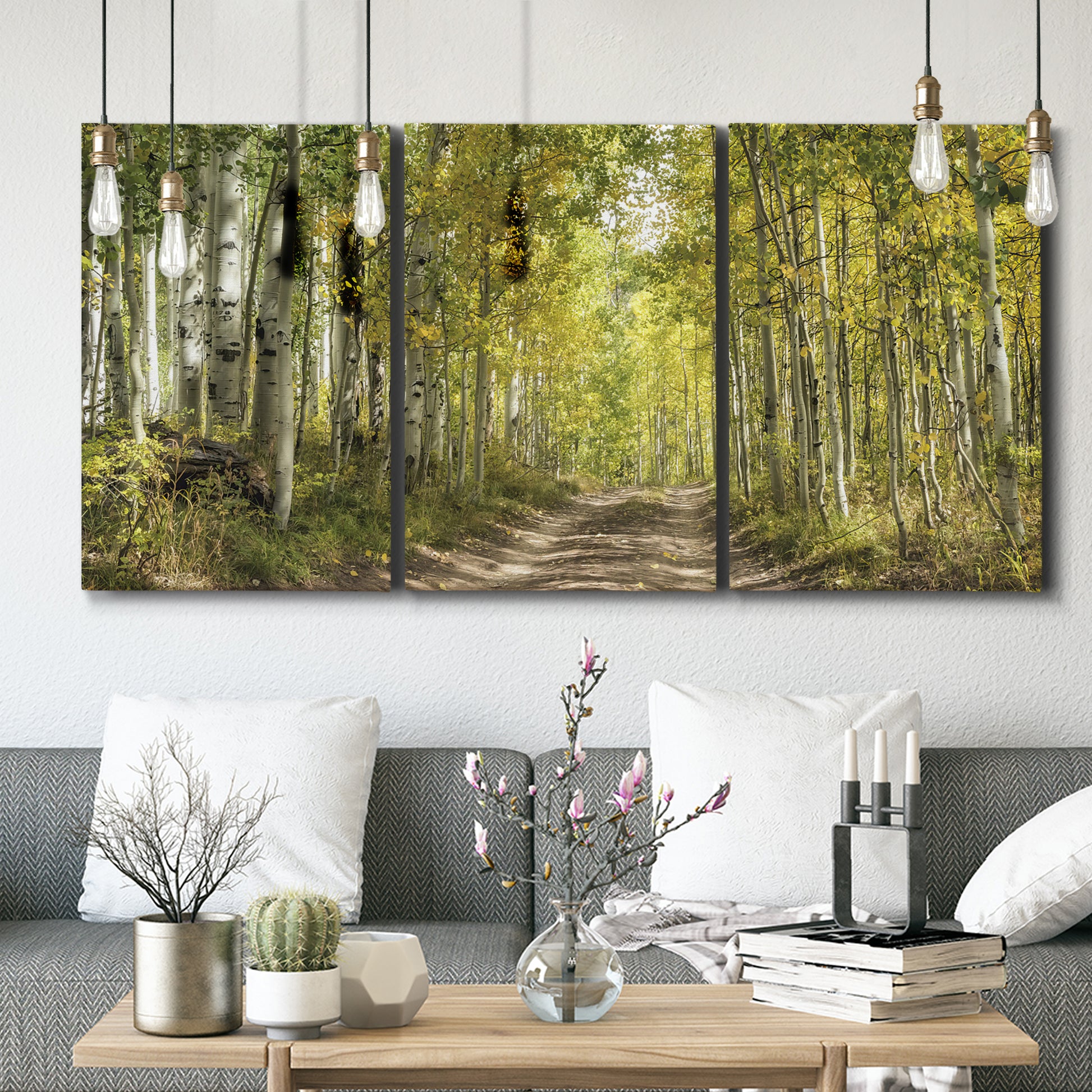 Three-panel canvas wall art featuring tree lined forest road photograph, displayed in a modern living room above seating.