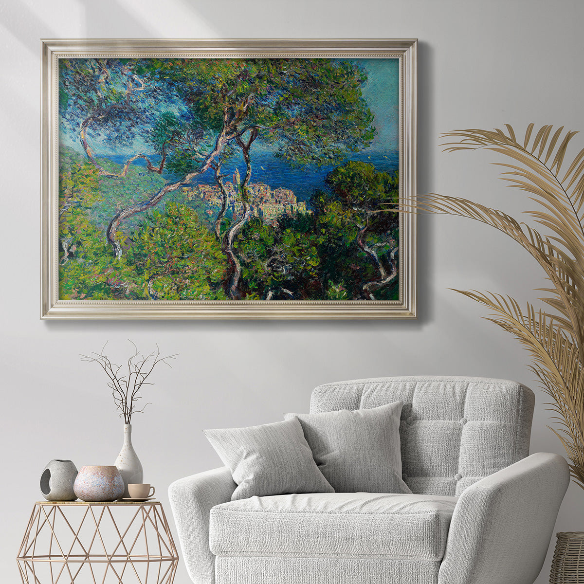 Impressionist Mediterranean coastal landscape by Claude Monet in an ornate champagne frame displayed in a bright interior setting.
