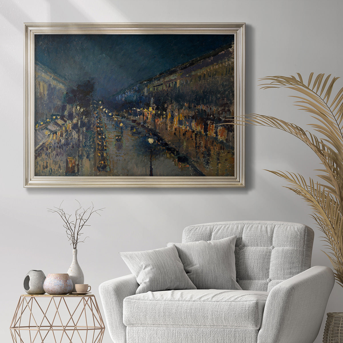 Impressionist nighttime Paris street scene by Camille Pissarro in an ornate champagne frame displayed in a bright interior setting.
