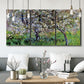 Three-panel canvas wall art featuring apple trees blooming beside water, displayed in a modern living room above seating.